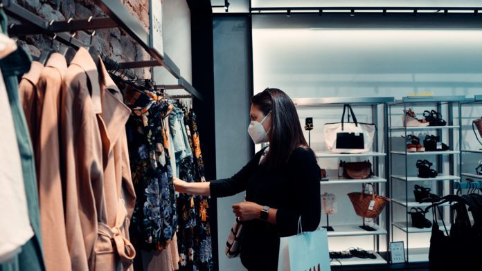 Customer experience changes during pandemic for consumers, like this woman shopping retail while wearing a mask.